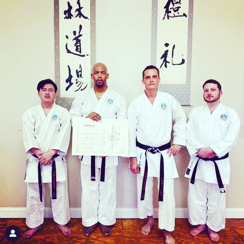 Sensei Jenkins with fellow black belts holding a rank diploma