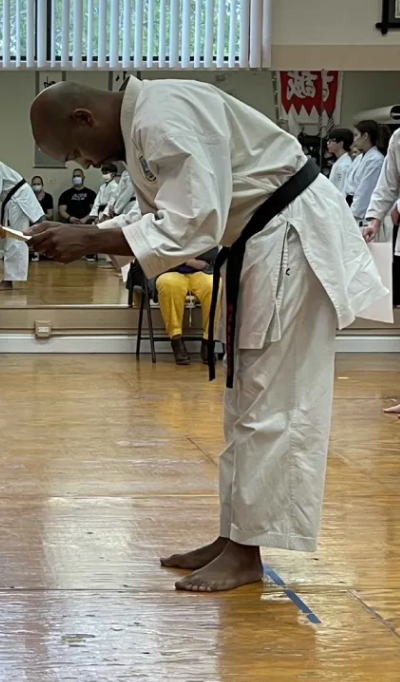 Sensei Jenkins bowing while receiving a certificate at a dojo ceremony