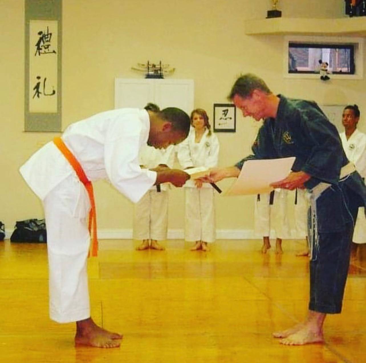 A young Sensei Jenkins bowing as he receives an orange belt certificate