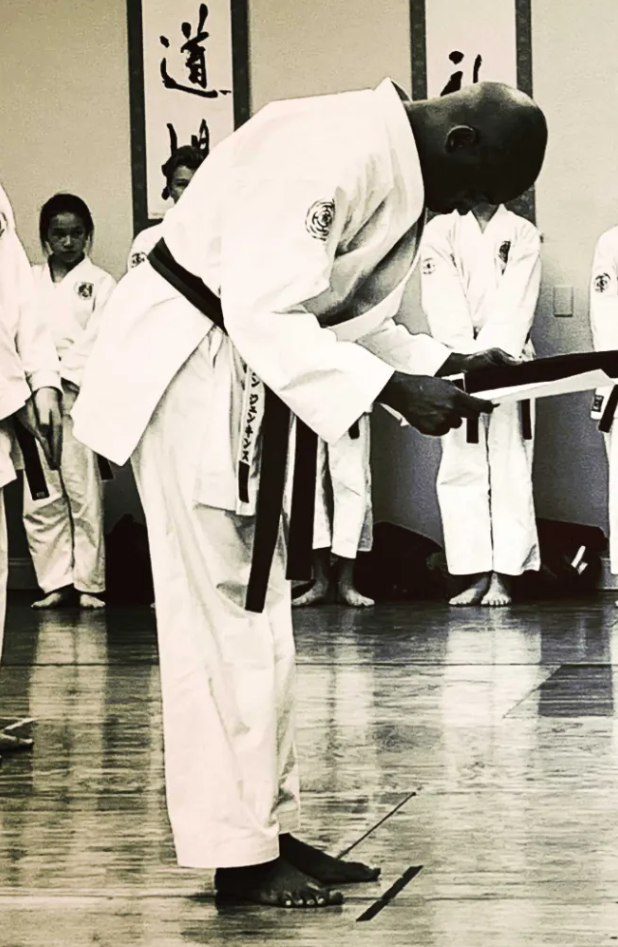 Sensei Kenneth Jenkins bowing to receive his black belt