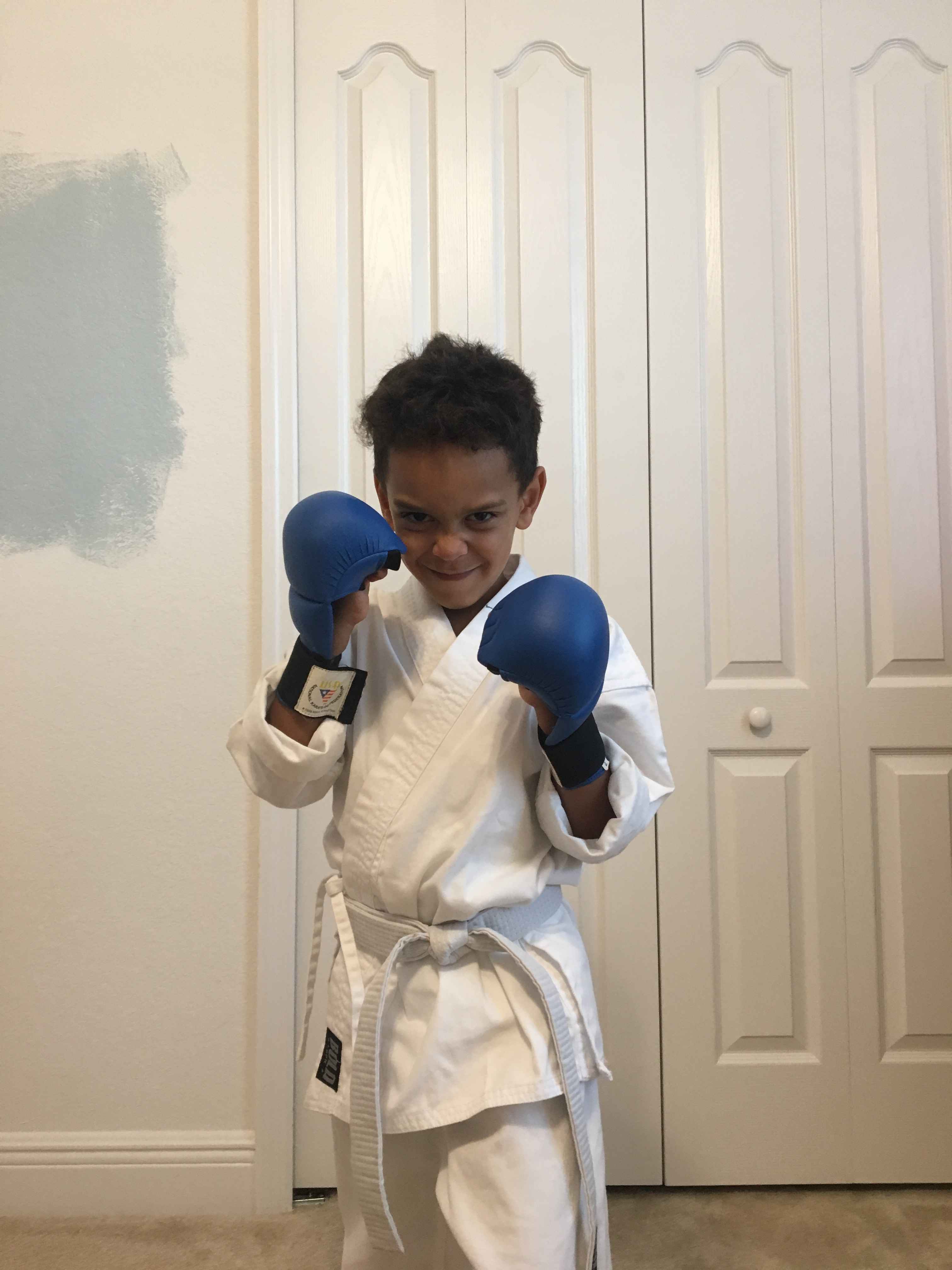 A young student in gi and sparring gloves in a fighting stance